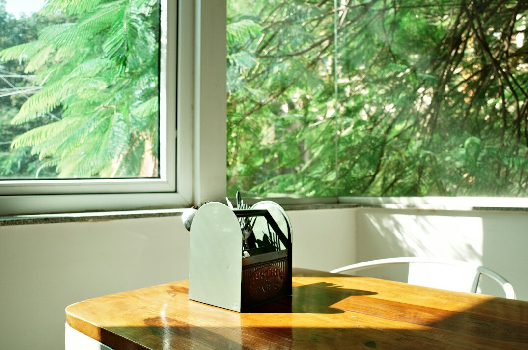 Sunny kitchen table with notebook, plant, coffee and wall calendar