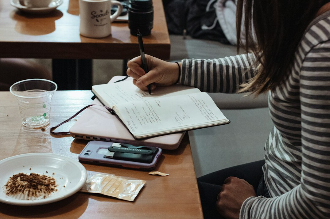 person writing in notebook expenses