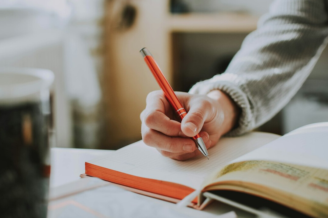 person writing budget on notebook